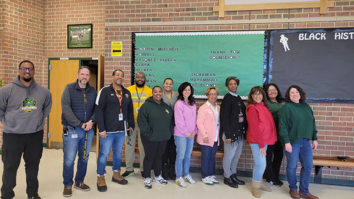 Group photo of school staff members expressing gratitude to their counselor, featured in a hallway decorated for Black History Month.