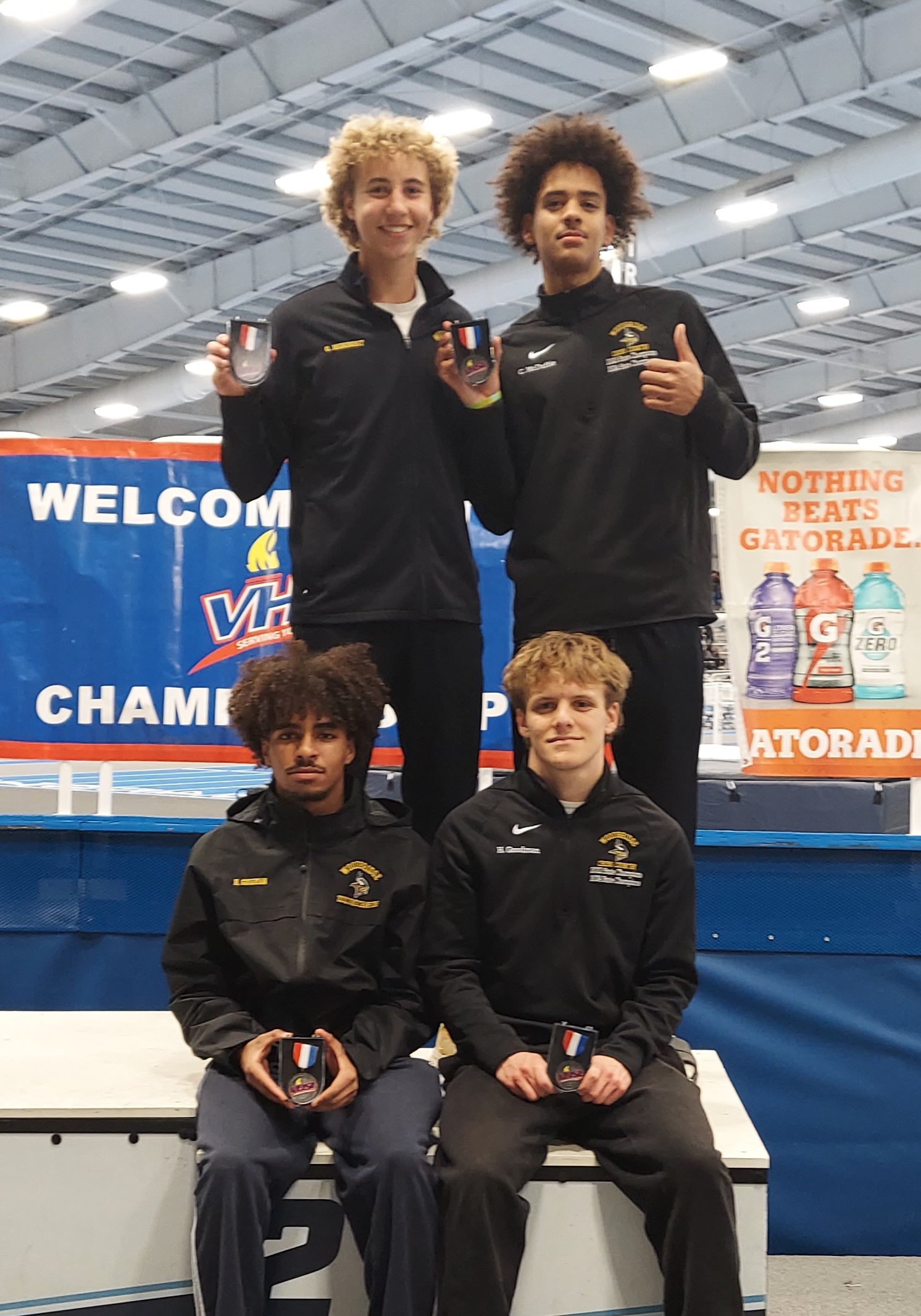 Four athletes proudly posing on a podium after winning medals at a championship event.