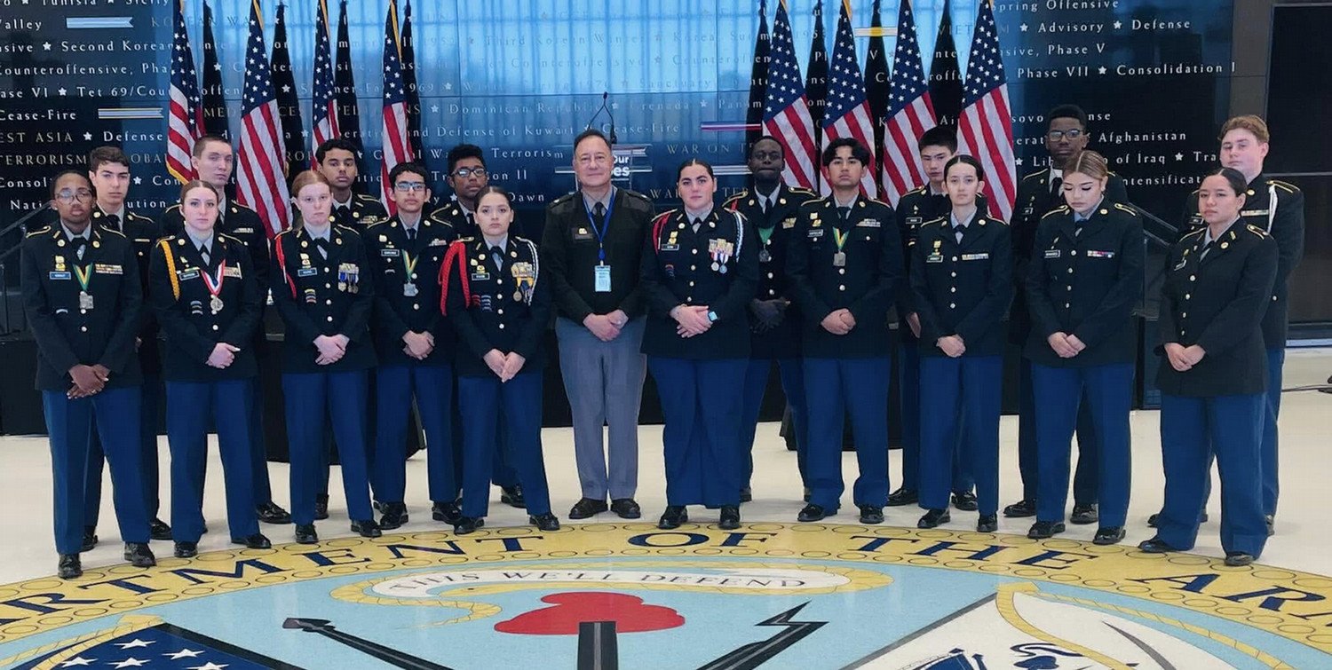 WSHS JROTC cadets and officials posing in front of the Department of the Army seal, with American flags in the background.