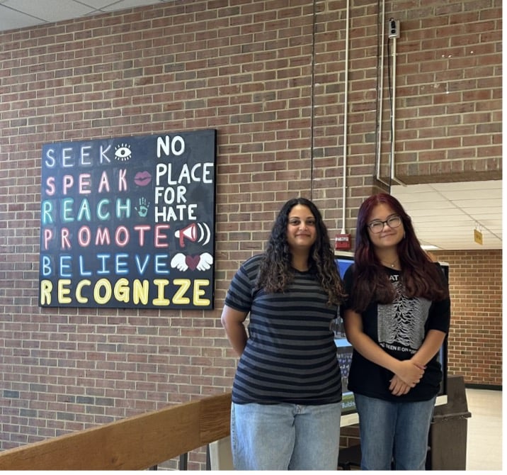 Saja Elsawalhi and Katherine Gordon in front of the no place for hate sign in the front lobby.