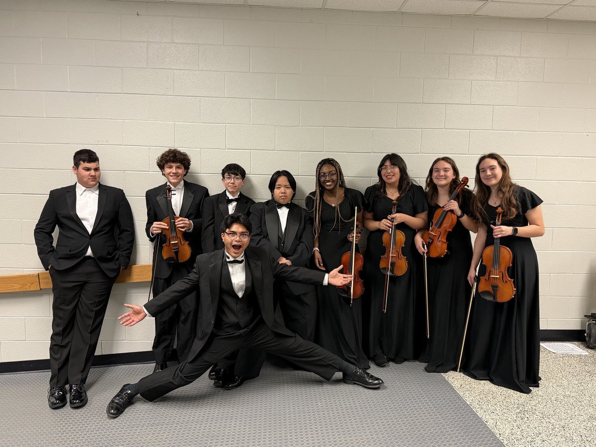 WSHS musicians in formal attire poses together with string instruments, showcasing camaraderie and celebration.