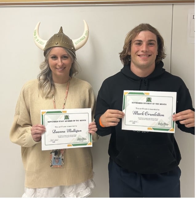 Deanna Mulligan wearing a Viking helmet and a sweatshirt stands next to a man holding a certificate for "Student of the Month," both smiling for the camera.